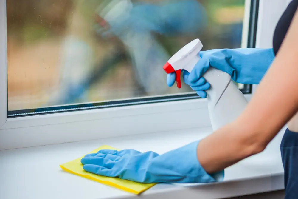 Hand in Handschuh wäscht ein Fenster