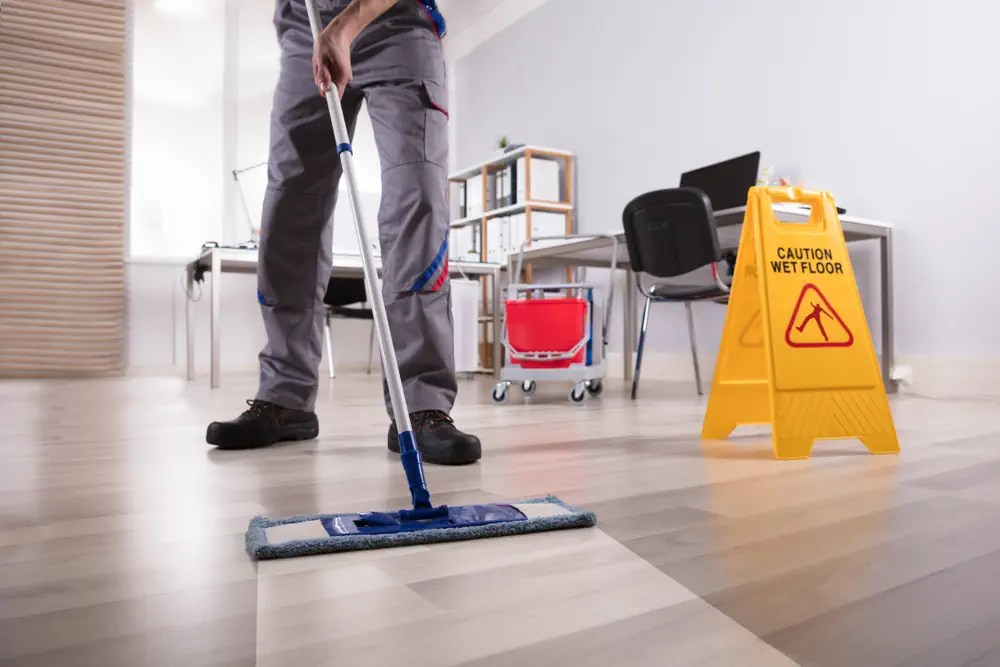 Reinigungskraft wischt Büroboden