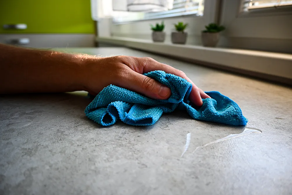 Mann wischt Küchentheke mit Mikrofasertuch